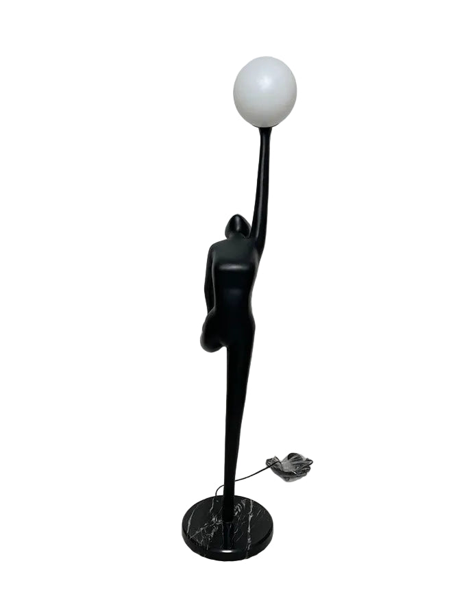 Black art deco-style lamp with a spherical light bulb on a white floor.