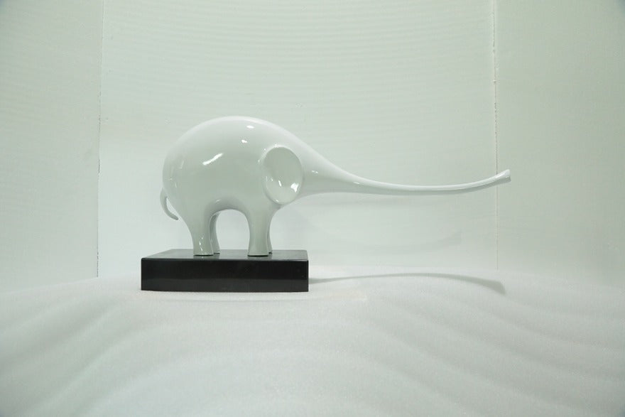White ceramic elephant sculpture on a black base against a white background