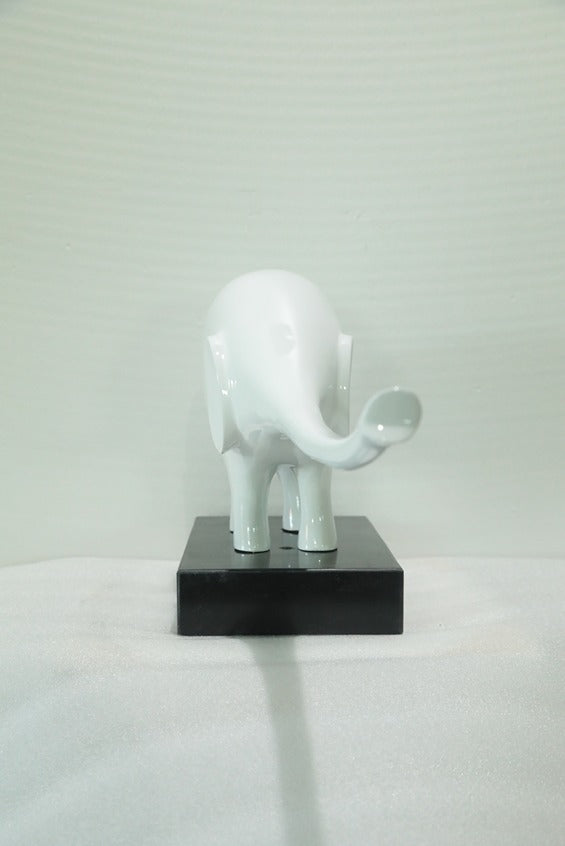 White elephant sculpture on a black base against a light gray background