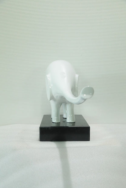 White elephant sculpture on a black base against a light gray background