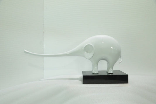 White elephant sculpture on a black base against a light gray background