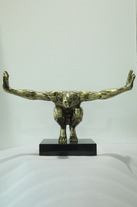 Bronze sculpture of a creature with outstretched arms on a white background