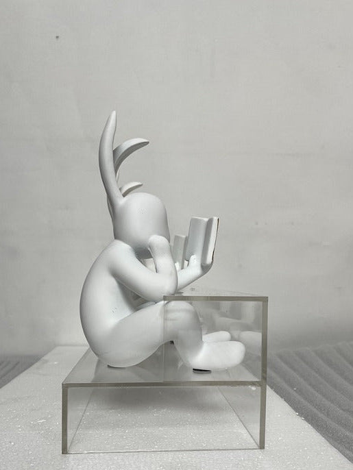 White abstract sculpture on a clear glass platform against a gray background