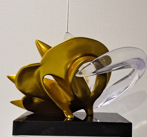 Gold and black decorative object on a white surface with a neutral background