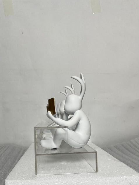White sculpture with antlers on a gray platform against a plain background