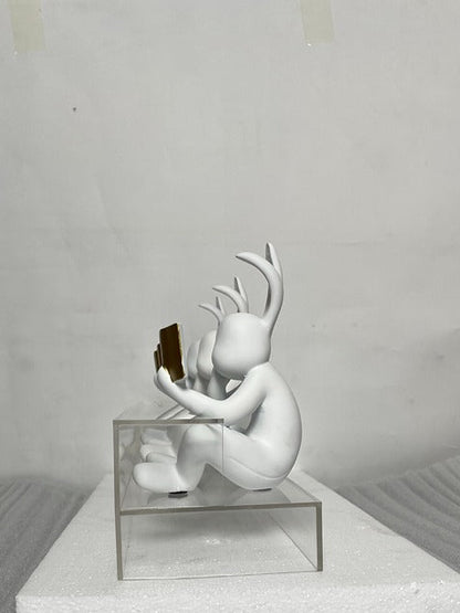 White sculpture with antlers on a gray platform against a plain background