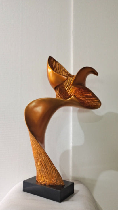 Gold bird-shaped sculpture on a white surface with a light gray background