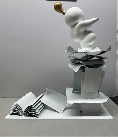 White sculpture with gold accent on a white surface