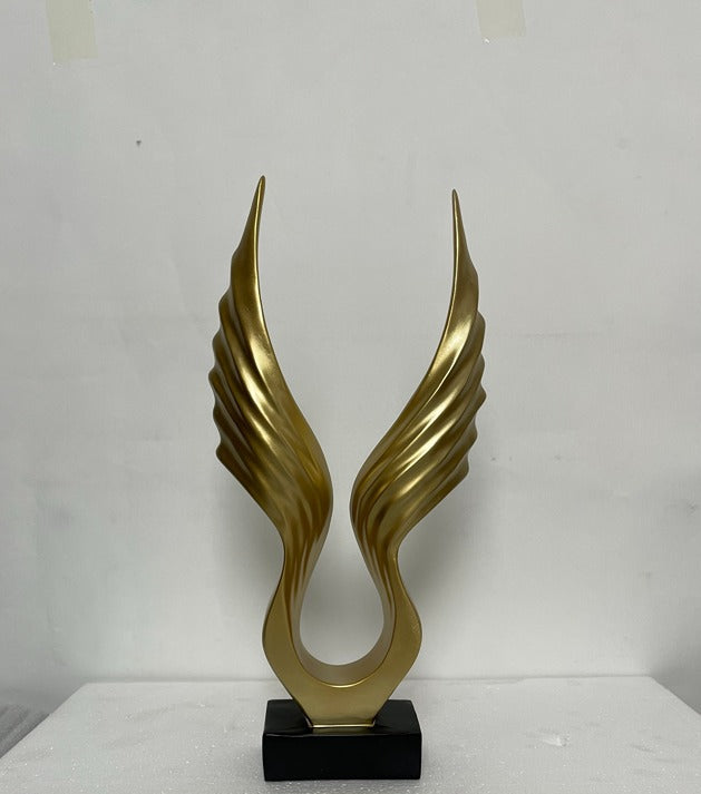 Gold abstract sculpture on a black base against a white background