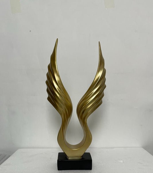 Gold abstract sculpture on a black base against a white background