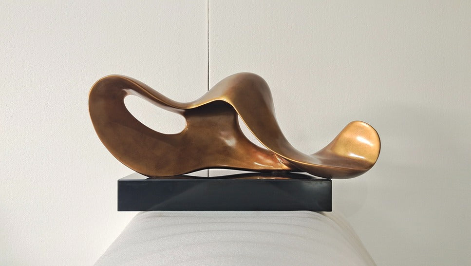 Abstract bronze sculpture on a black base against a neutral background