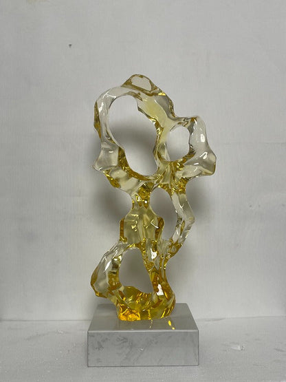 Abstract glass sculpture on a gray base against a white background