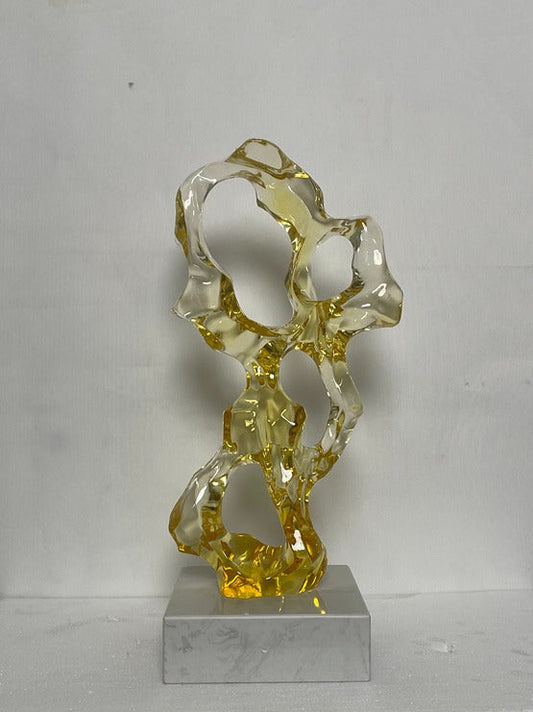 Abstract glass sculpture on a gray base against a white background