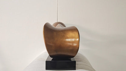 Bronze sculpture on a white pedestal against a plain background