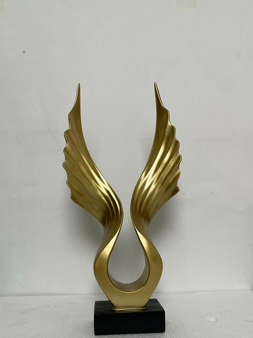 Gold winged sculpture on a black base against a white background