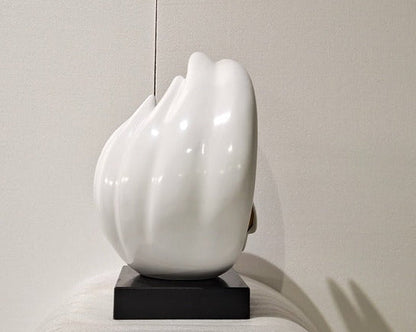 White ceramic sculpture on a black base against a neutral background