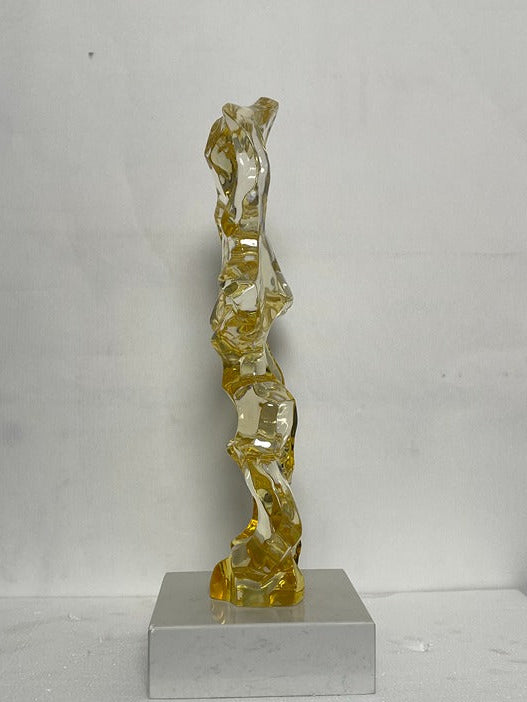 Abstract glass sculpture on a gray pedestal against a white background
