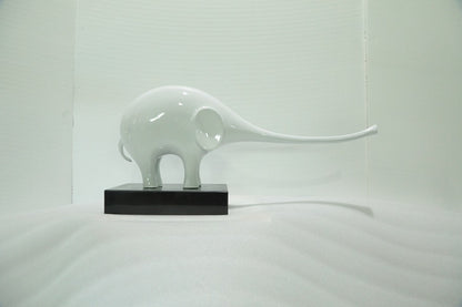 White ceramic elephant sculpture on a black base against a white background