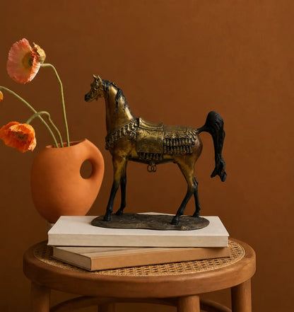 Bronze horse figurine with saddle and tassels, next to a terracotta vase with orange poppies