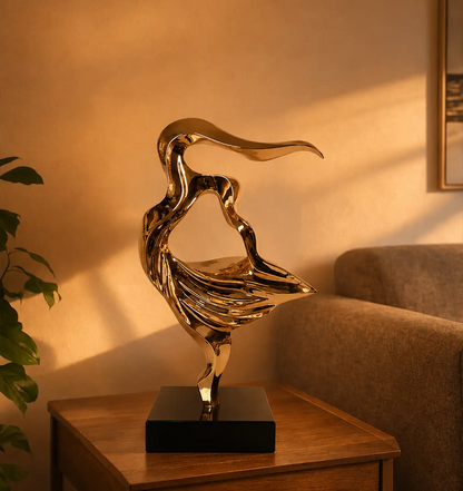 Abstract gold sculpture on a wooden table next to a green plant and a brown sofa