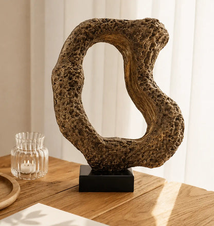 Abstract sculpture with a textured, organic shape and an open center, on a black base