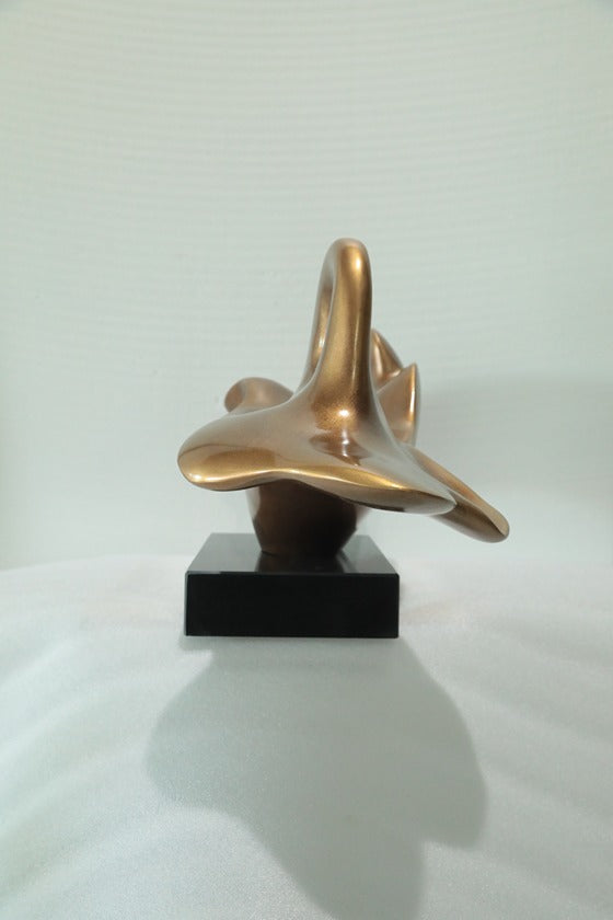 Bronze abstract sculpture on a black base against a white background
