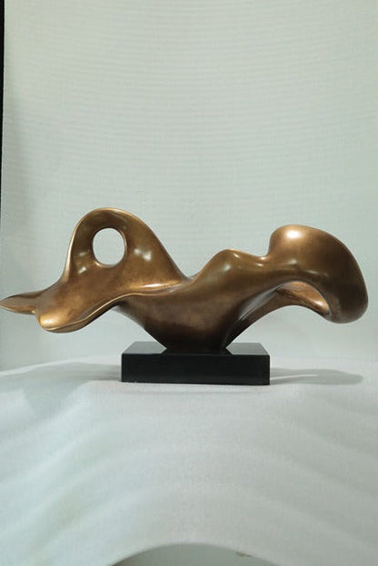 Bronze abstract sculpture on a white surface with a neutral background