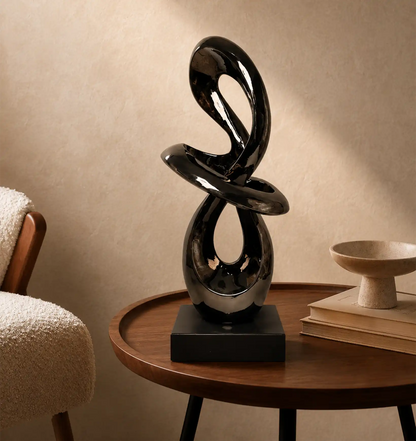 Black abstract sculpture on a wooden side table next to a cream chair and books